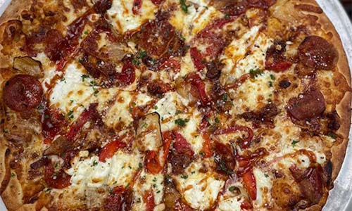Close-up of a pizza topped with pepperoni, cheese, and vegetables on a golden crust.