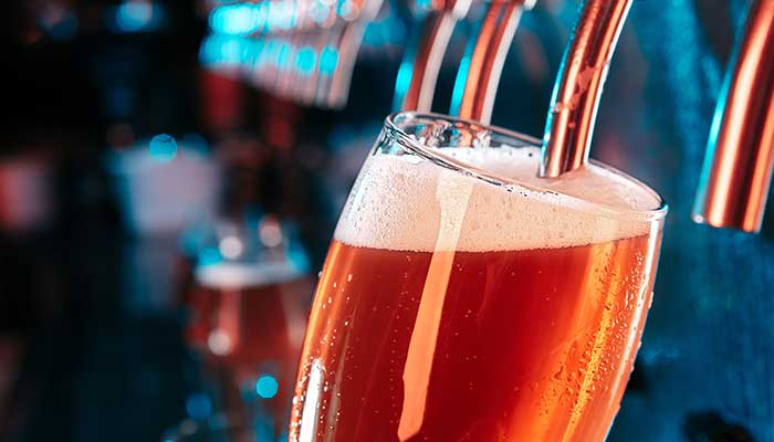 A glass of beer being filled from a tap at Carriage Towne Bar & Grille's bar menu counter.